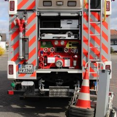 Rotes Feuerwehrfahrzeug, ein Löschfahrzeug (LF 20), mit geöffneter Hecktür mit Beladung.
