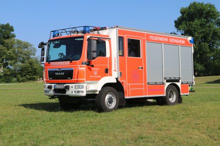 Rotes Feuerwehrfahrzeug, ein Löschfahrzeug (LF 20), steht auf einer Rasenfläche.