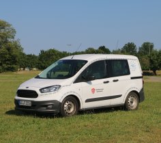 Weißes Feuerwehrfahrzeug, ein PKW, steht auf einer Rasenfläche.