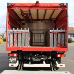 Rotes Feuerwehrfahrzeug, ein Schlauchwagen Katastrophenschutz (SW-KatS), geöffnete Hecktür mit Beladung.