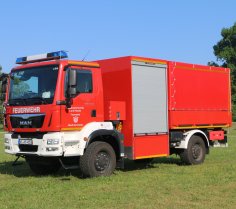 Rotes Feuerwehrfahrzeug, ein Schlauchwagen Katastrophenschutz (SW-KatS), steht auf einer Rasenfläche.