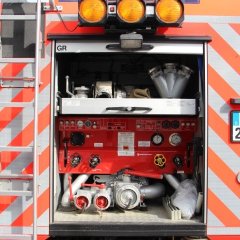 Rotes Feuerwehrfahrzeug, ein Tanklöschfahrzeug (TLF 24/50), geöffnete Hecktür mit Beladung.
