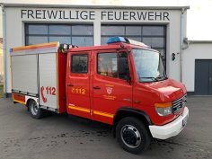 Rotes Feuerwehrfahrzeug, ein Tragkraftspritzenfahrzeug (TSF-W), steht vor einem Feuerwehrgerätehaus.