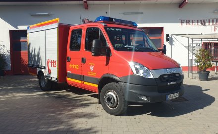 Rotes Feuerwehrfahrzeug, ein Tragkraftspritzenfahrzeug (TSF-W), steht vor einem Feuerwehrgerätehaus.