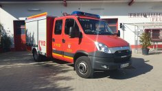 Rotes Feuerwehrfahrzeug, ein Tragkraftspritzenfahrzeug (TSF-W), steht vor einem Feuerwehrgerätehaus.